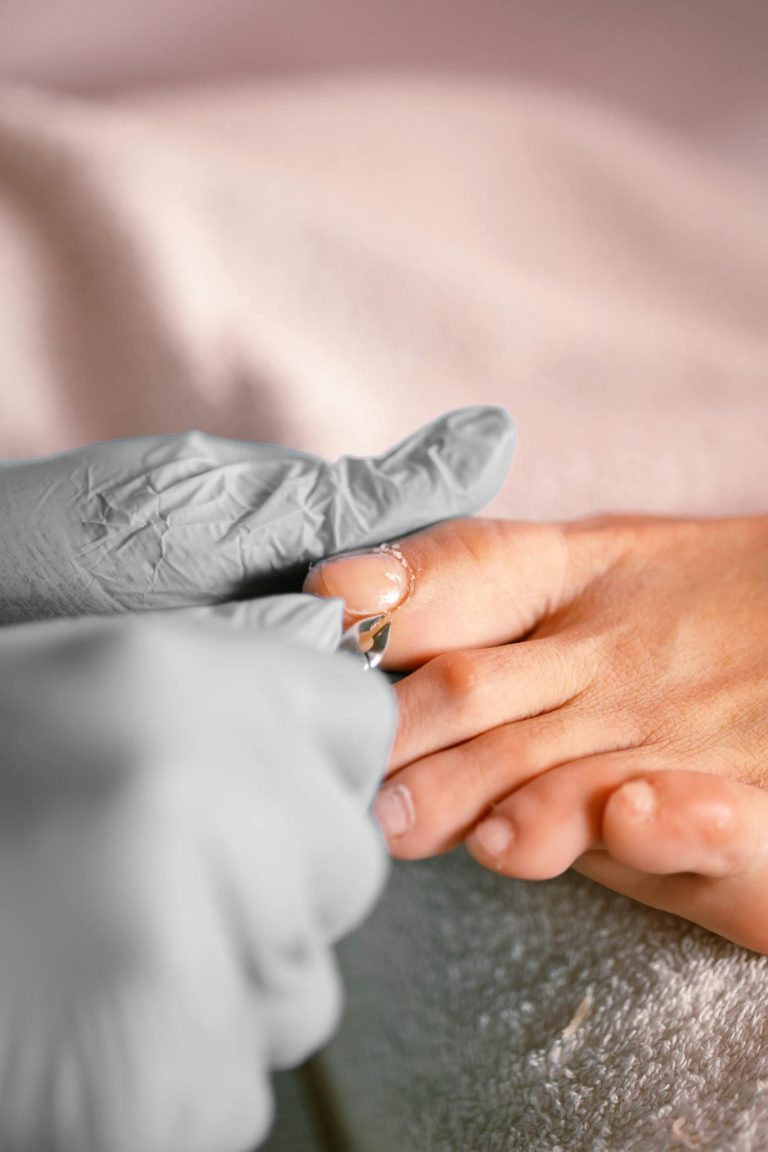 Close-up of a pedicure session with protective gloves and focus on the toenail treatment.